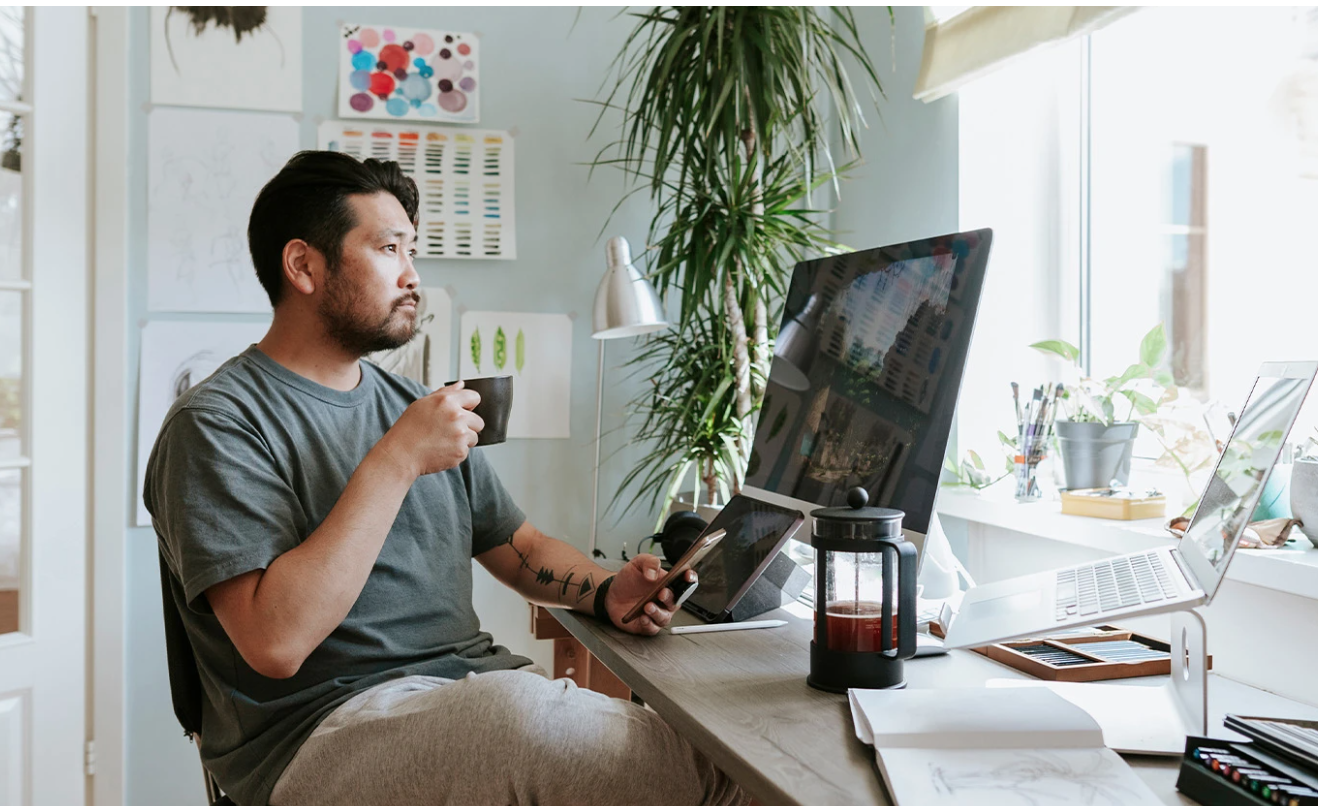 Photo of man sitting at home office desk with view out the window