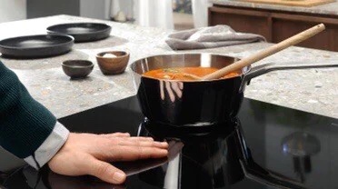 Photo of man with hand on induction cooktop